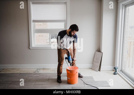 Mann das Mischen von Zement in Eimer mit hand Mixer Stockfoto