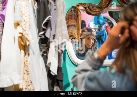 Spiegelbild der jungen Frau, die versucht, auf Vintage Kleidung in Sparsamkeitspeicher Stockfoto