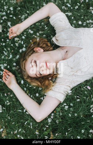 Frau liegend auf Blüten bedeckte Gras, Ansicht von oben Stockfoto