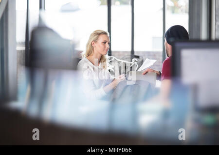 Weibliche und männliche Kollegen in Diskussion im Büro Stockfoto