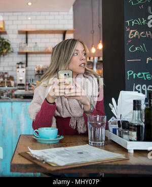 Frau sitzt im Cafe, Smartphone, Weg suchen Stockfoto