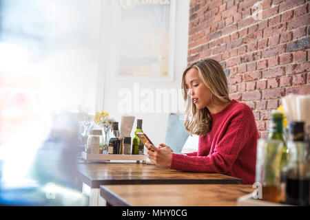 Frau sitzt im Cafe, am Smartphone suchen Stockfoto