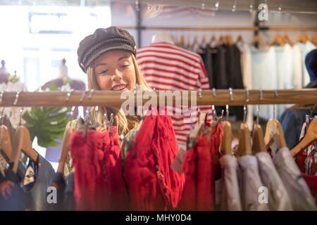 Junge Frau shopping, Kleidung auf der Schiene im Shop Stockfoto