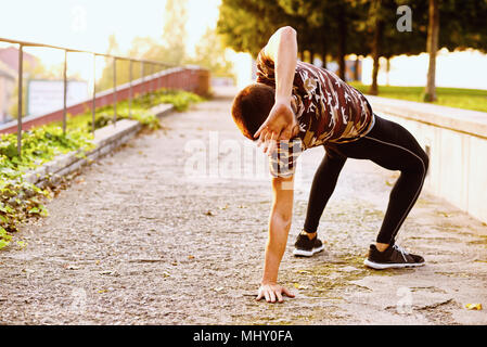 Junger Mann Training im Freien, nach hinten dehnen Stockfoto