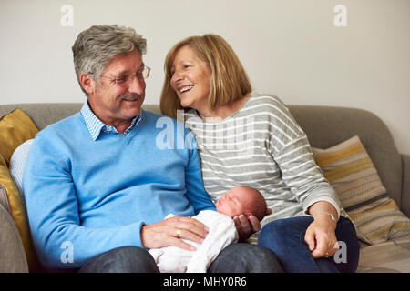 Großeltern auf dem Sofa mit Baby Enkelin Stockfoto