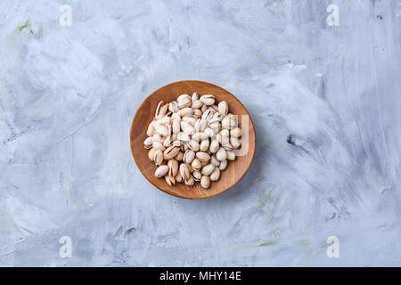 Gesalzene Pistazien auf einer Holzplatte auf weißem Hintergrund, Ansicht von oben, Nahaufnahme, selektiven Fokus. Leckere bio Snack. Gesunde Ernährung für ein gesundes Leben. Fo Stockfoto