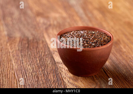 Ansicht von oben Nahaufnahme von Leinsamen in Houten auf Braun rustikal Hintergrund isoliert, selektiver Fokus, senkrecht. Nahrhaft und deitary I Stockfoto