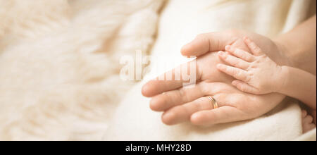 Weibliche Hand die Hand ihrer neugeborenen Babys halten. Mutter mit ihrem Kind. Mutterschaft, Familie, geburt Konzept. Kopieren Sie Platz für Ihren Text. Banner Stockfoto