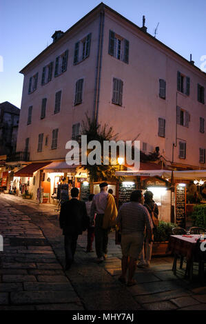 Touristen, die auf der Suche an einem Baugruppenträger oat ein Geschenk Shop in einer schmalen Straße, die Rue Georges Clemenceau in der alten Stadt, Calvi auf Korsika, einer französischen Insel im Sou Stockfoto