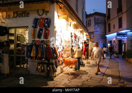 Touristen, die auf der Suche an einem Baugruppenträger oat ein Geschenk Shop in einer schmalen Straße, die Rue Georges Clemenceau in der alten Stadt, Calvi auf Korsika, einer französischen Insel im Sou Stockfoto