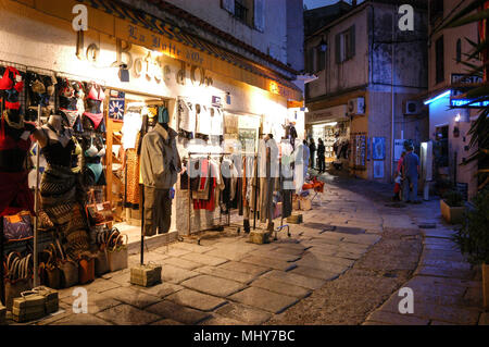 Touristen, die auf der Suche an einem Baugruppenträger oat ein Geschenk Shop in einer schmalen Straße, die Rue Georges Clemenceau in der alten Stadt, Calvi auf Korsika, einer französischen Insel im Sou Stockfoto