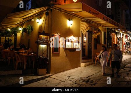 Touristen, die auf der Suche an einem Baugruppenträger oat ein Geschenk Shop in einer schmalen Straße, die Rue Georges Clemenceau in der alten Stadt, Calvi auf Korsika, einer französischen Insel im Sou Stockfoto