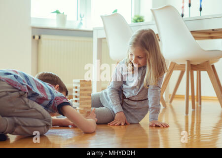 Zwei glückliche Geschwister spielen ein Spiel mit Holzklötzen zu Hause freudig Stockfoto