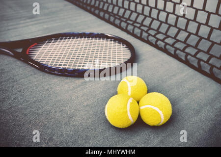 Tennisschläger, Net und drei gelbe Tennisbälle auf blauen Beton Tennisplatz Stockfoto