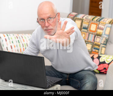 Eine verärgerte älterer Mann mit einem Laptop in Home Stockfoto