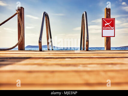 Red kein Tauchen mit Kopie der den Platz auf einer hölzernen Pier neben einem Meer Leiter vor einem Meer und Himmel Hintergrund Stockfoto