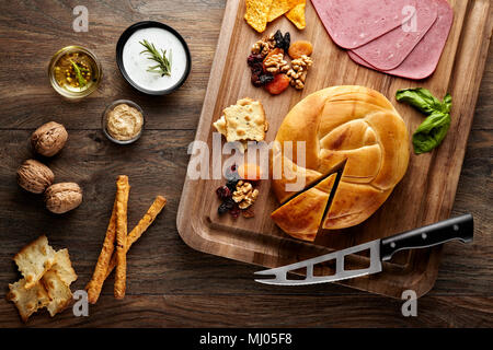 Türkische geräucherter Käse auf einem Holztisch mit Requisiten aus Holz Schneidebrett, Käsemesser, Walnüsse, getrocknete Früchte, Schinken und Olivenöl Stockfoto