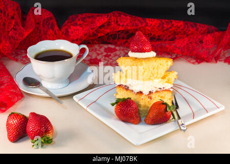 Stück hausgemachten Kuchen mit Erdbeeren und Sahne auf Platte mit Tasse Tee-Konzept der Sommer Stockfoto