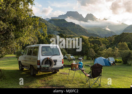 MONKS COWL, SÜDAFRIKA - 18. MÄRZ 2018: ein Zelt und die Fahrzeuge am Campingplatz bei Monks Cowl in den Drakensbergen. Cathedral Peak (links) und Mönche C Stockfoto