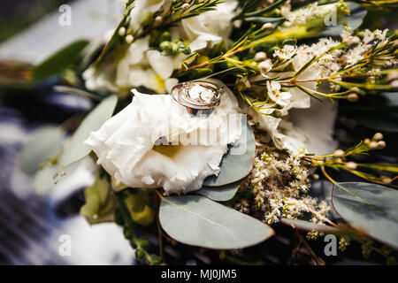 Gold Trauringe auf einen Strauß weißer Blumen Stockfoto