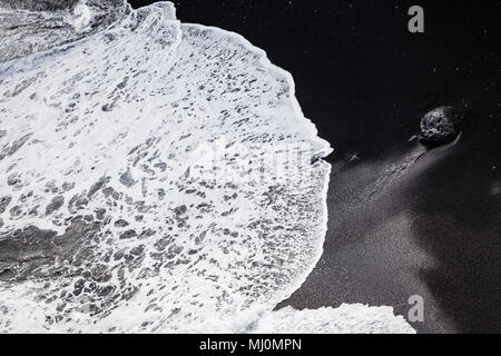 Wave waschen über dem schwarzen Sandstrand im Süden Islands Stockfoto