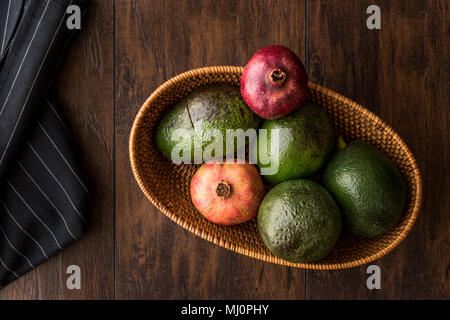 Granatapfel und Avocado in einem hölzernen Warenkorb (Bio-Konzept) Stockfoto