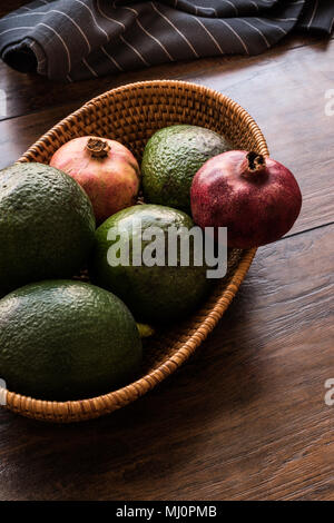 Granatapfel und Avocado in einem hölzernen Warenkorb (Bio-Konzept) Stockfoto