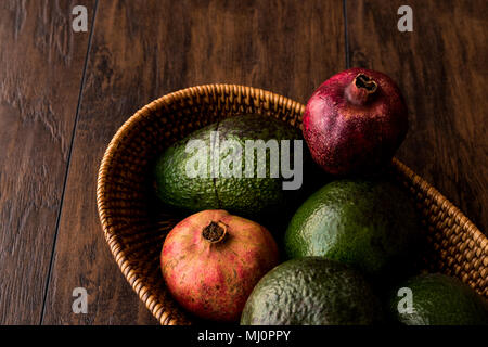 Granatapfel und Avocado in einem hölzernen Warenkorb (Bio-Konzept) Stockfoto