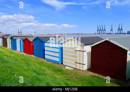 Bunten Badekabinen am Hafen in Harwich, Essex. Sonnigen Tag. Mai 2018. Hafen von Felixstowe Krane im Hintergrund sichtbar. Stockfoto