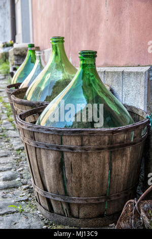 Oprtalj, Istrien (Istra), Kroatien - Große leere Flaschen Wein in Holz- Träger neben der Wand Stockfoto