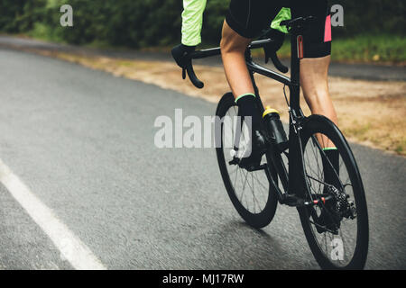 Männliche Athlet Radfahren auf der Landstraße. 7/8 Schuß des Menschen Reiten Fahrrad auf nasser Straße, Üben für einen Wettbewerb. Stockfoto