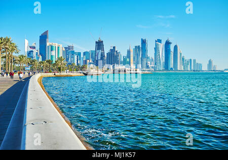 DOHA, Katar - Februar 13, 2018: Die Welle Mauer erstreckt sich entlang der Corniche, schützen und auch von der Bank für müde Wanderer, Stockfoto