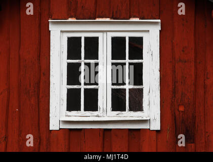 Nahaufnahme eines älteren geschlossenes Fenster mit weißem Fenster Sprint auf einer rot - Holz Wand gemalt. Stockfoto