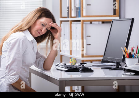 Seitenansicht eines reifen Geschäftsfrau Kopfschmerzen Leiden am Arbeitsplatz Stockfoto