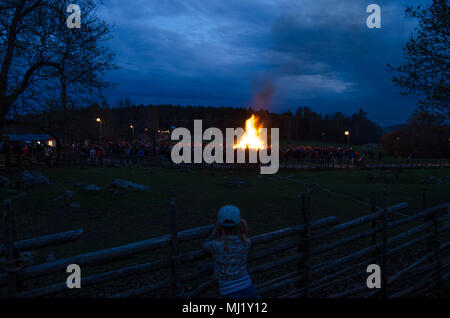 Stockholm, Schweden, 30. April 2018. Die Menschen feiern die Ankunft des Frühlings mit einem Lagerfeuer. Ein Mädchen schaut in die Menge und Lagerfeuer. Stockfoto