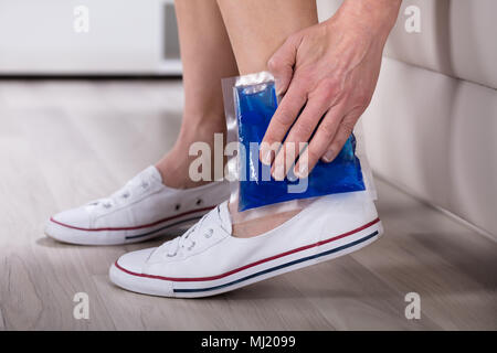 Nahaufnahme der Frau Hand Cool Gel Pack auf Ihrem Knöchel Stockfoto