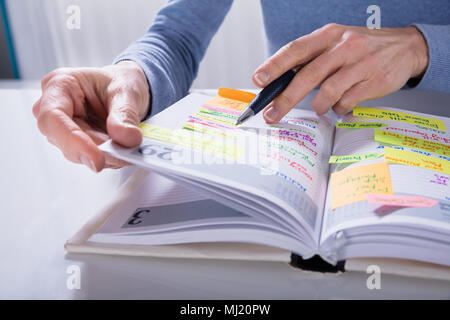Nahaufnahme einer Frau schreiben Termine im Kalender Tagebuch auf weißem Schreibtisch Stockfoto