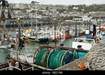 Der britischen Fischereiflotte in Newlyn mit Trawler und Netze im Vordergrund und eine Vielzahl von Booten und die Stadt von Newlyn im Hintergrund. Stockfoto