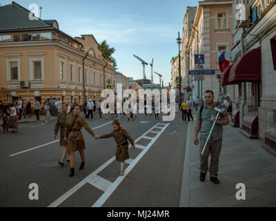 Moskau, Russland - Mai 9, 2016: Drei Mädchen in militärischen historische Kleidung und ein Mann mit Porträt eines Vorfahren sind zu Fuß entlang der Straße Bolshaya Ordynka Str Stockfoto