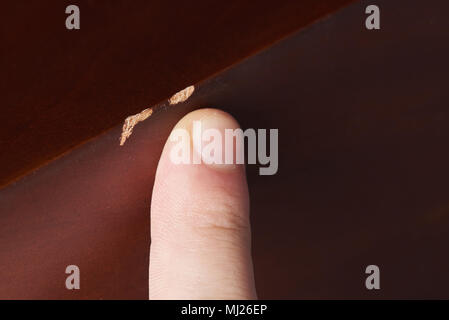 Zeigt mit dem Finger Kratzer auf Holzmöbeln. Holz- Oberfläche verkratzt Stockfoto