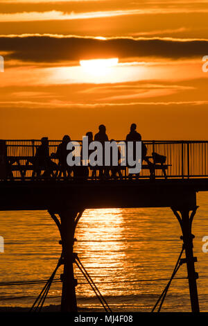 Aberystwyth Wales UK, Freitag, 04. Mai 2018 Deutschland Wetter: Menschen mit einem Drink am Ende von Seaside Aberystwyyth's Pier an einem warmen Abend, Silhouetted, wie die Sonne über die Cardigan Bay Die Bank Holiday Wochenende prognostiziert ist bei schönem Wetter, mit der Aussicht auf rekordverdächtige Temperaturen in London und in den Südosten Foto © Keith Morris/Alamy Live Aktuelles Sets Stockfoto