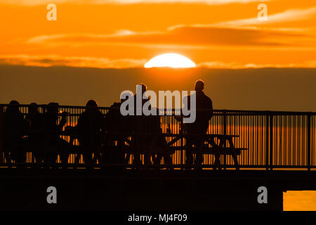 Aberystwyth Wales UK, Freitag, 04. Mai 2018 Deutschland Wetter: Menschen mit einem Drink am Ende von Seaside Aberystwyyth's Pier an einem warmen Abend, Silhouetted, wie die Sonne über die Cardigan Bay Die Bank Holiday Wochenende prognostiziert ist bei schönem Wetter, mit der Aussicht auf rekordverdächtige Temperaturen in London und in den Südosten Foto © Keith Morris/Alamy Live Aktuelles Sets Stockfoto