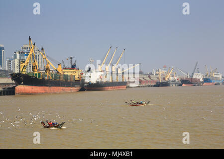 Frachtschiffe säumen die Ufer des Flusses Hafen Yangon in Myanmar (Burma) mit der Stadt Yangon Gebäude im Hintergrund. Stockfoto