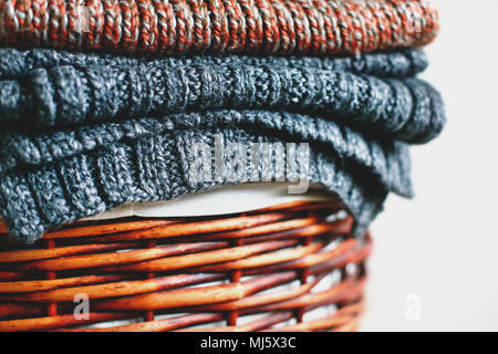 Stapel der gestrickte Winter plaids auf Stroh Korb auf weißem Hintergrund. Close Up. Stockfoto