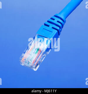 Blaue Netzwerkkabel mit RJ-45-Anschluss auf einem blauen Hintergrund. Stockfoto