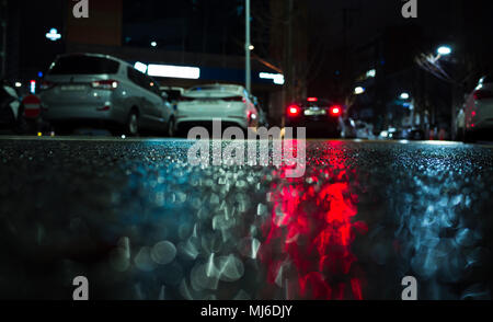 Abstrakte Nacht Stadt Hintergrund mit roten Bremsleuchten Reflexion auf nassem Asphalt Stockfoto