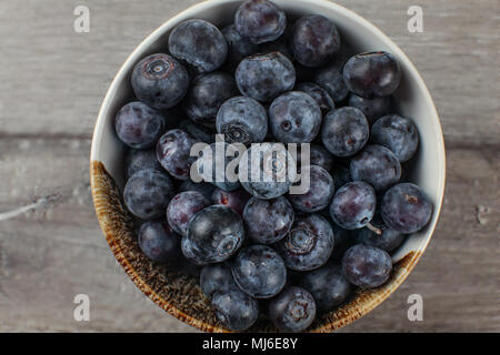 Nahaufnahme Detail der kleine Schüssel mit blaubeeren von oben gesehen gefüllt, auf grau Holz Schreibtisch platziert. Stockfoto