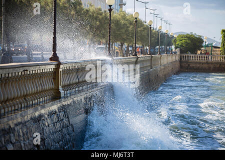 Meer Wellen gegen die Brüstung einer Straße in windigen Tag: Stürmisches Wetter brechen. Stockfoto