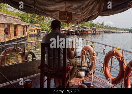 Alappuzha, Kerala/Indien - 15. April 2018: ein Kapitän ist die Lenkung ein Haus Boot durch die Wasserstraßen von Alappuzah. Stockfoto