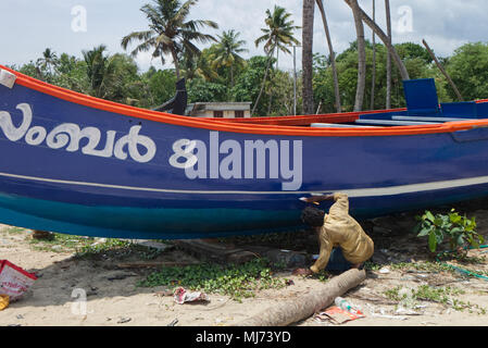 Kochi (Cochin) Kerala/Indien - 15. April 2018: Ein Mann ist malerarbeiten seinem Fischerboot am Strand im Bundesstaat Kerala, Indien. Stockfoto